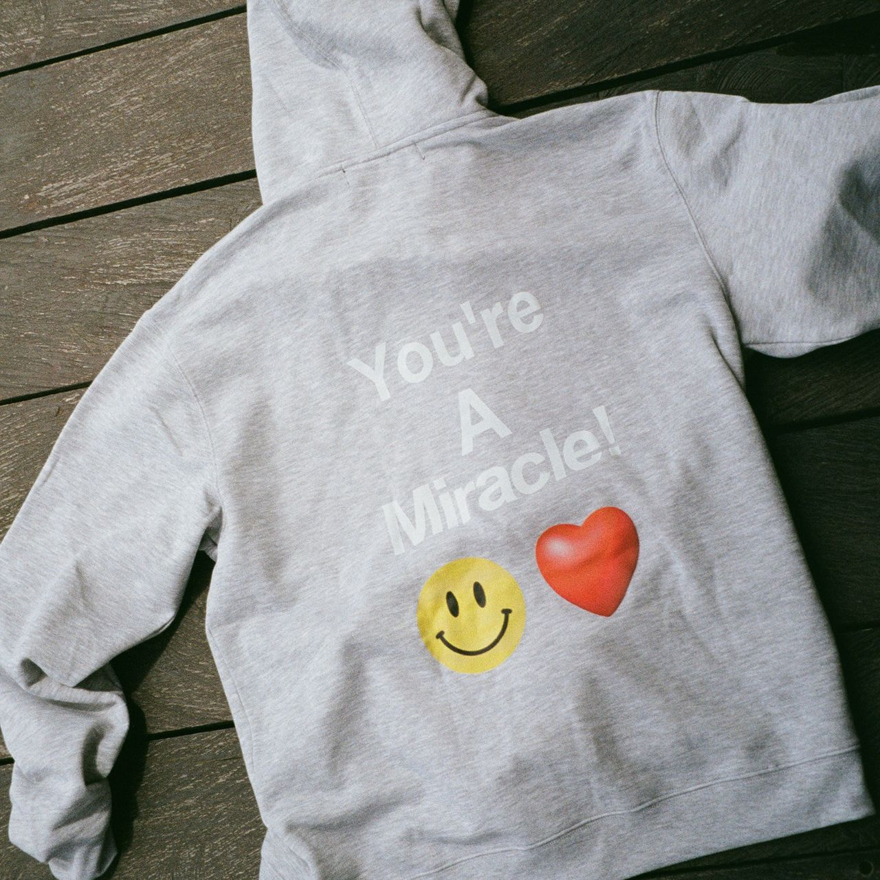 A gray hoodie with a “‘You’re a miracle” print on the back.
